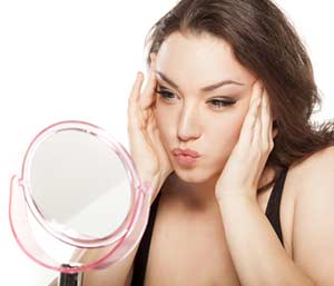 Young woman in front of the mirror tightens her face